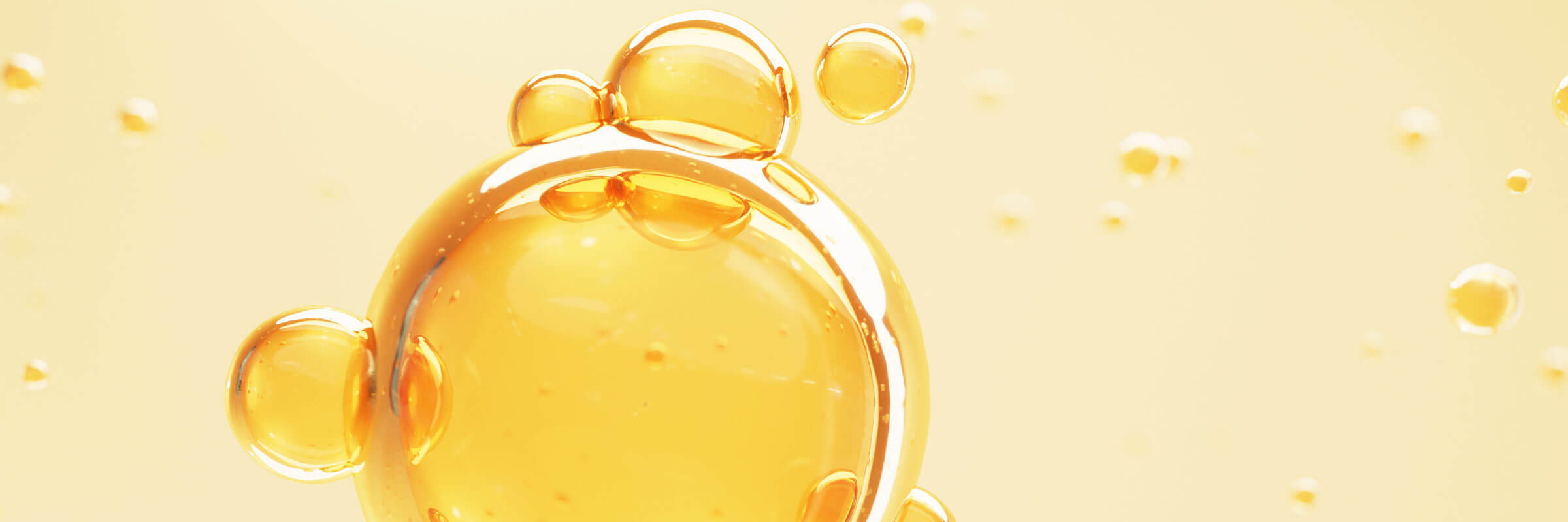 Golden vitamin C serum droplets pooled on a pale yellow surface