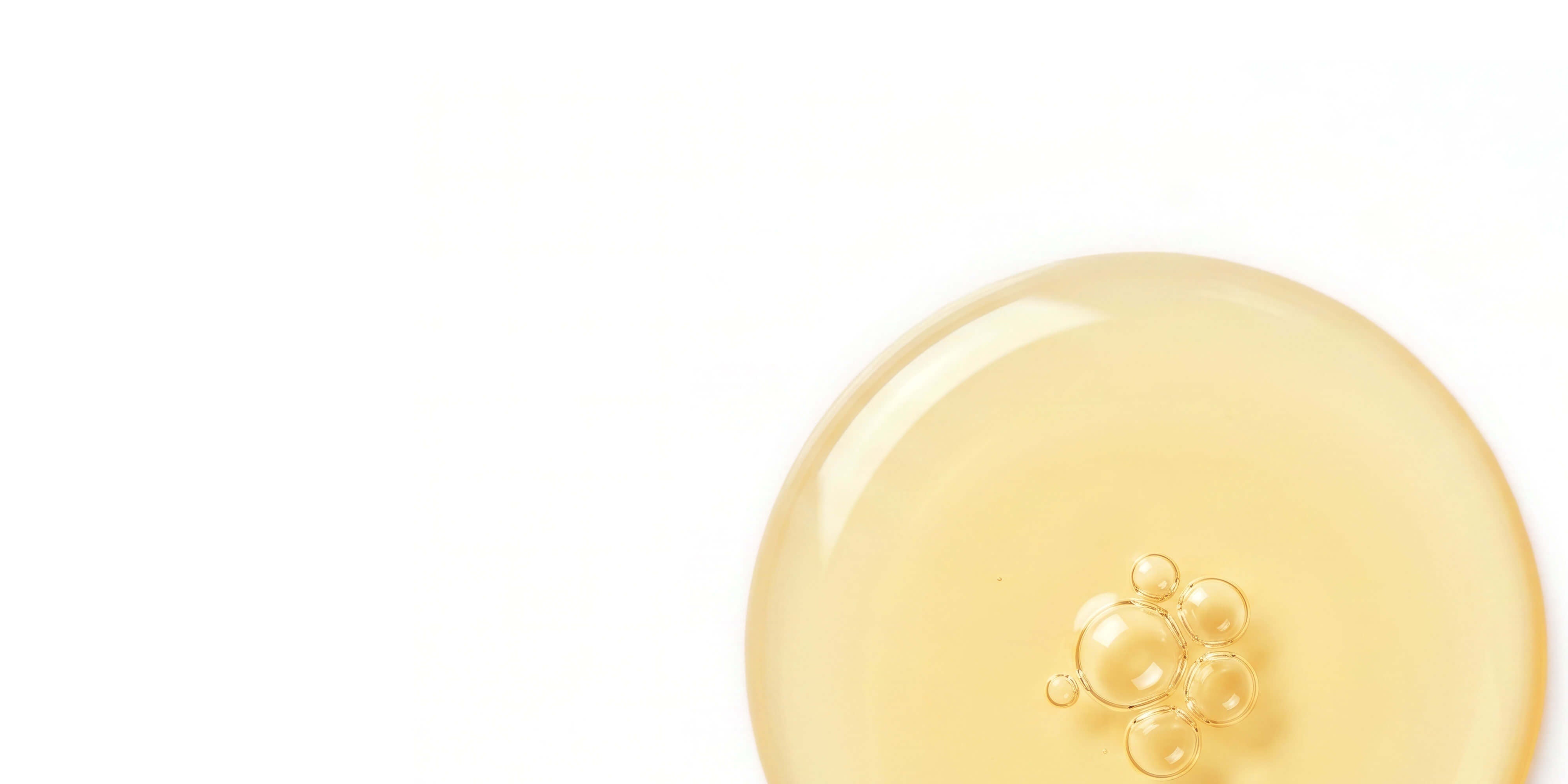 Golden botanical oil forming a large translucent sphere with smaller bubbles